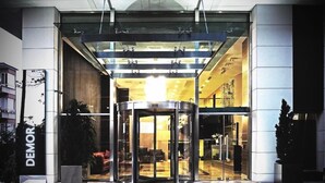 A hotel entrance with a revolving door, glass facade, and a reception area visible inside. - Demora Hotel (Ankara)