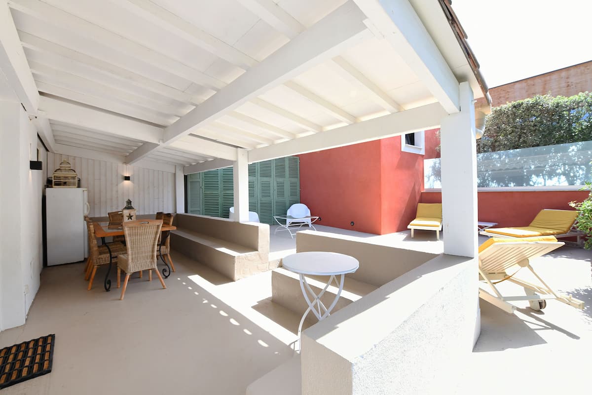 An outdoor patio with a table and chairs, a small white table, and a yellow chair.