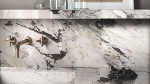 A bathroom with a marble sink and a black trash bin.