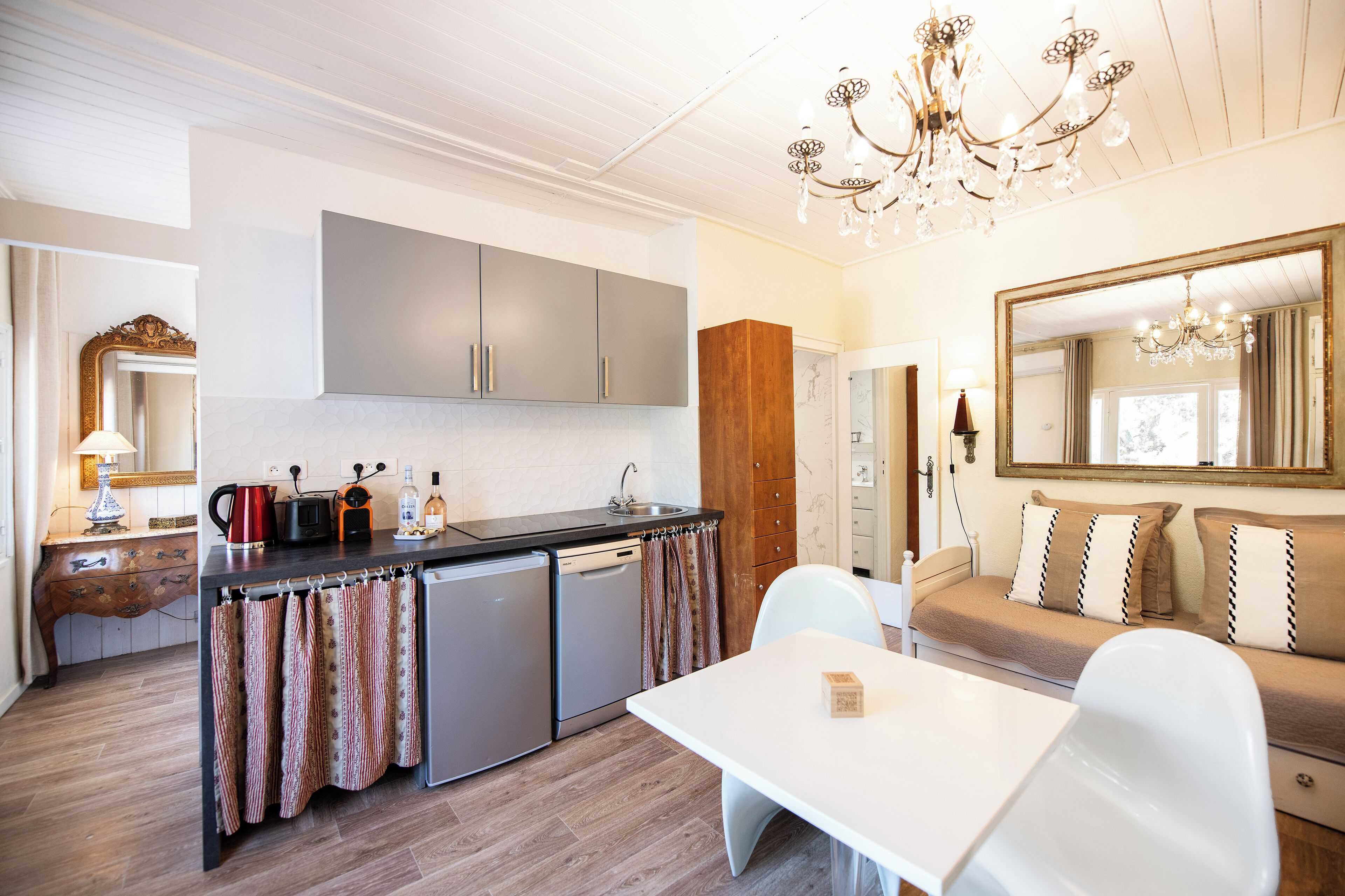 A modern kitchen with grey cabinets, a dishwasher, and a dining area with a white table and chairs.