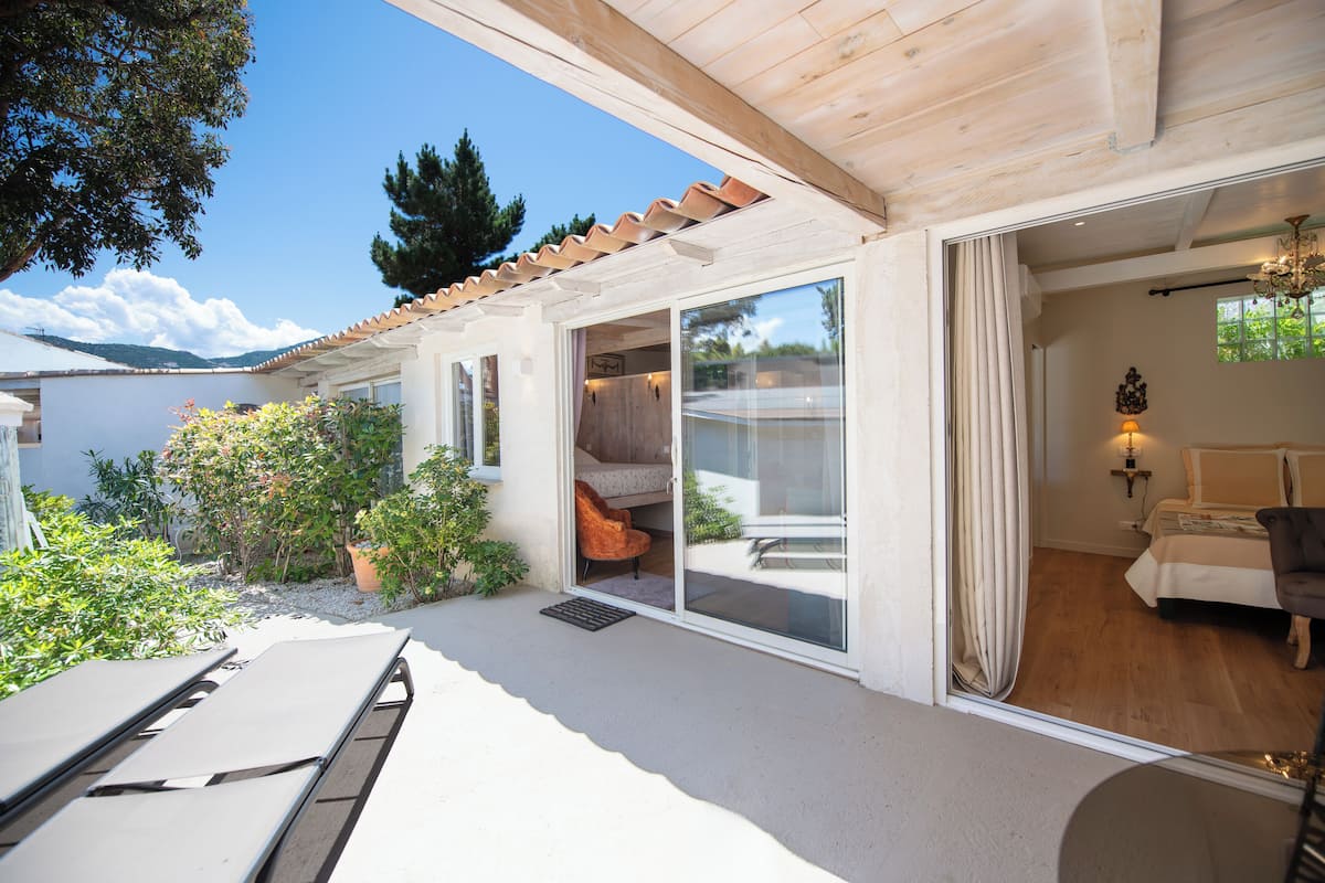 A modern villa with a patio, a bedroom with a bed and a chair, and a view of the lake.