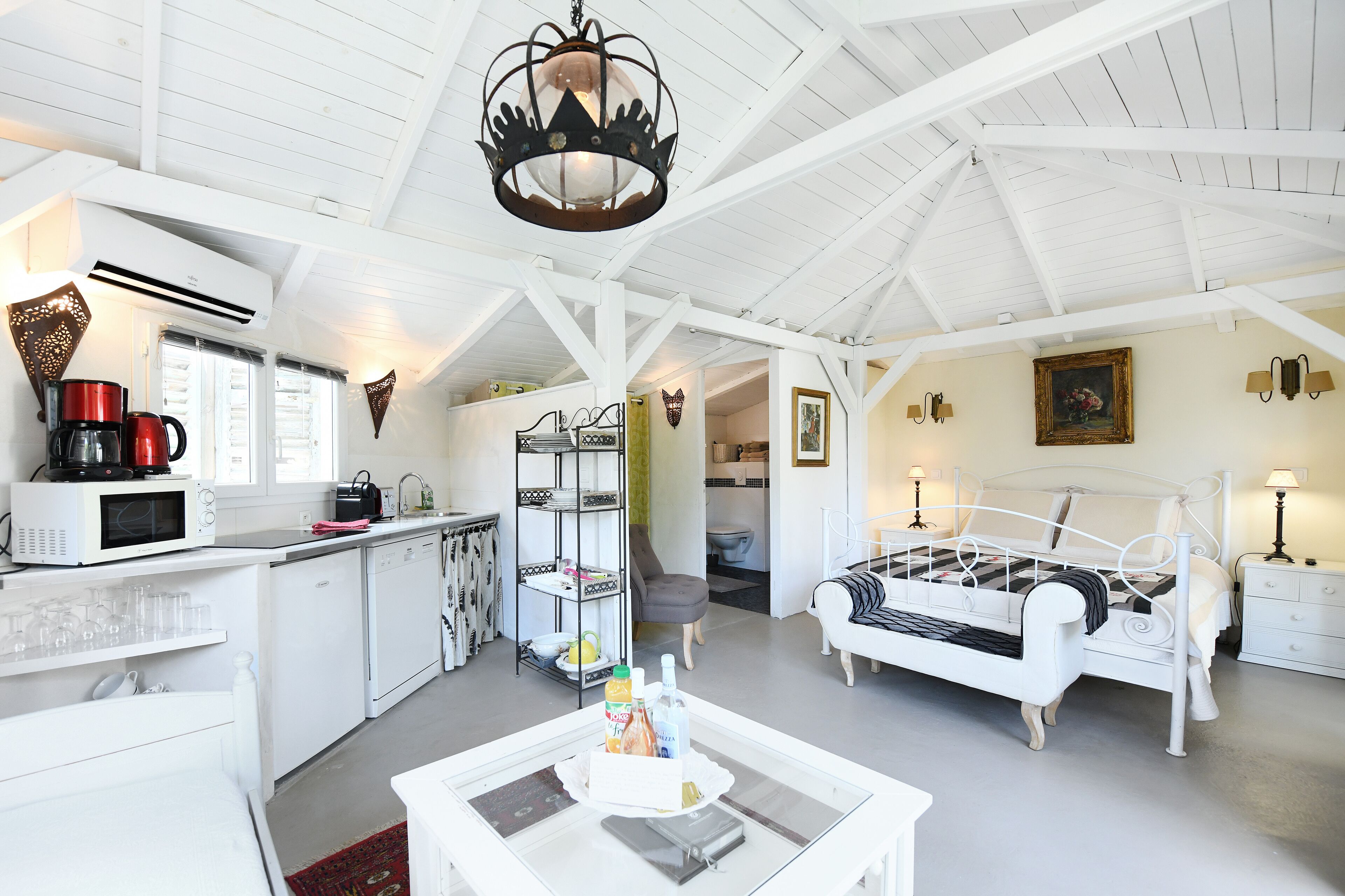 Un intérieur blanc comprenant un lit, une cuisine et un coin repas.