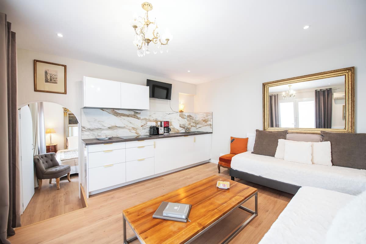 A modern hotel room with a bed, a desk, a chair, a coffee machine, and a TV.