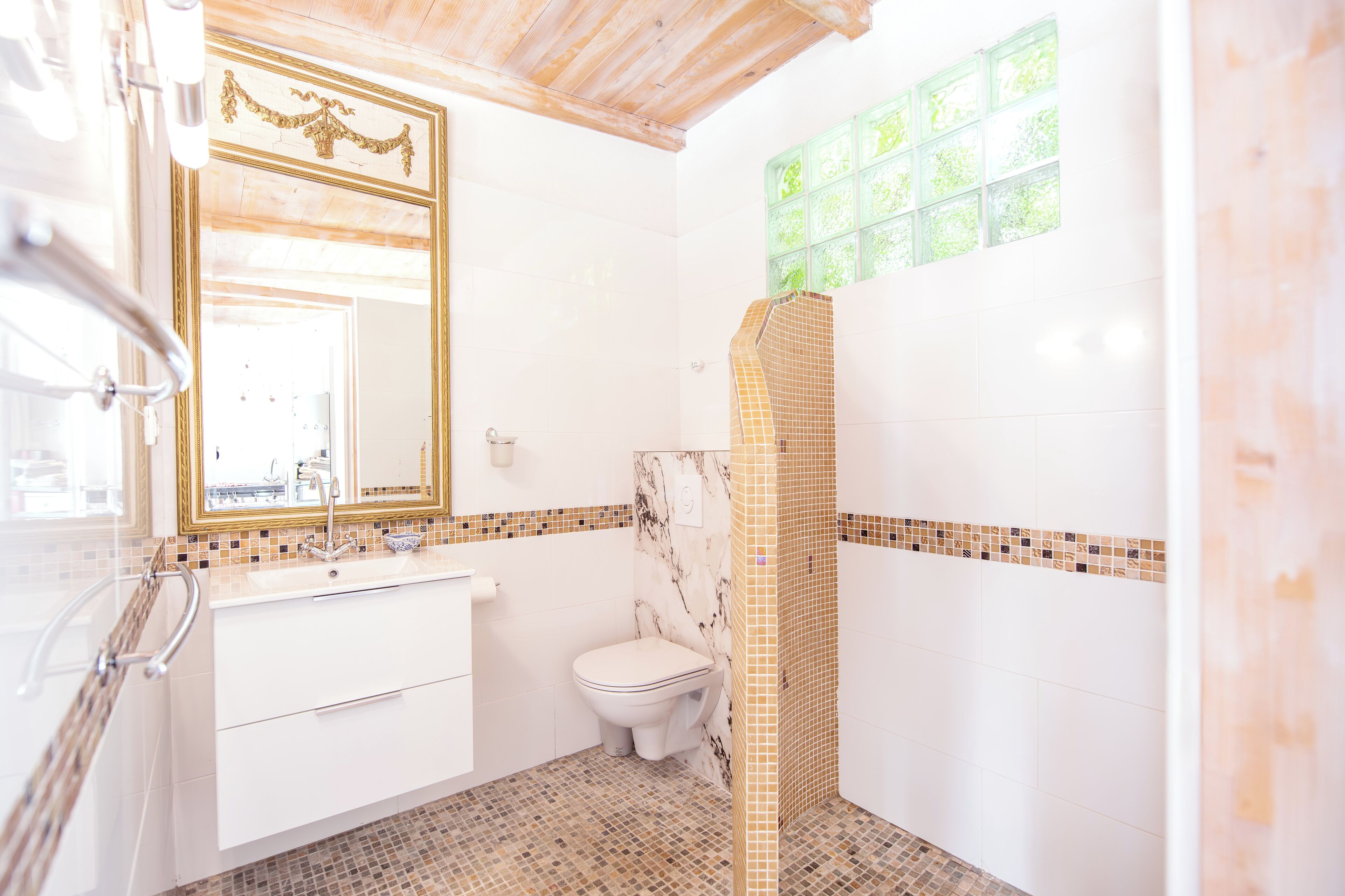 A bathroom with a white vanity, a toilet, and a shower area with mosaic tiles.