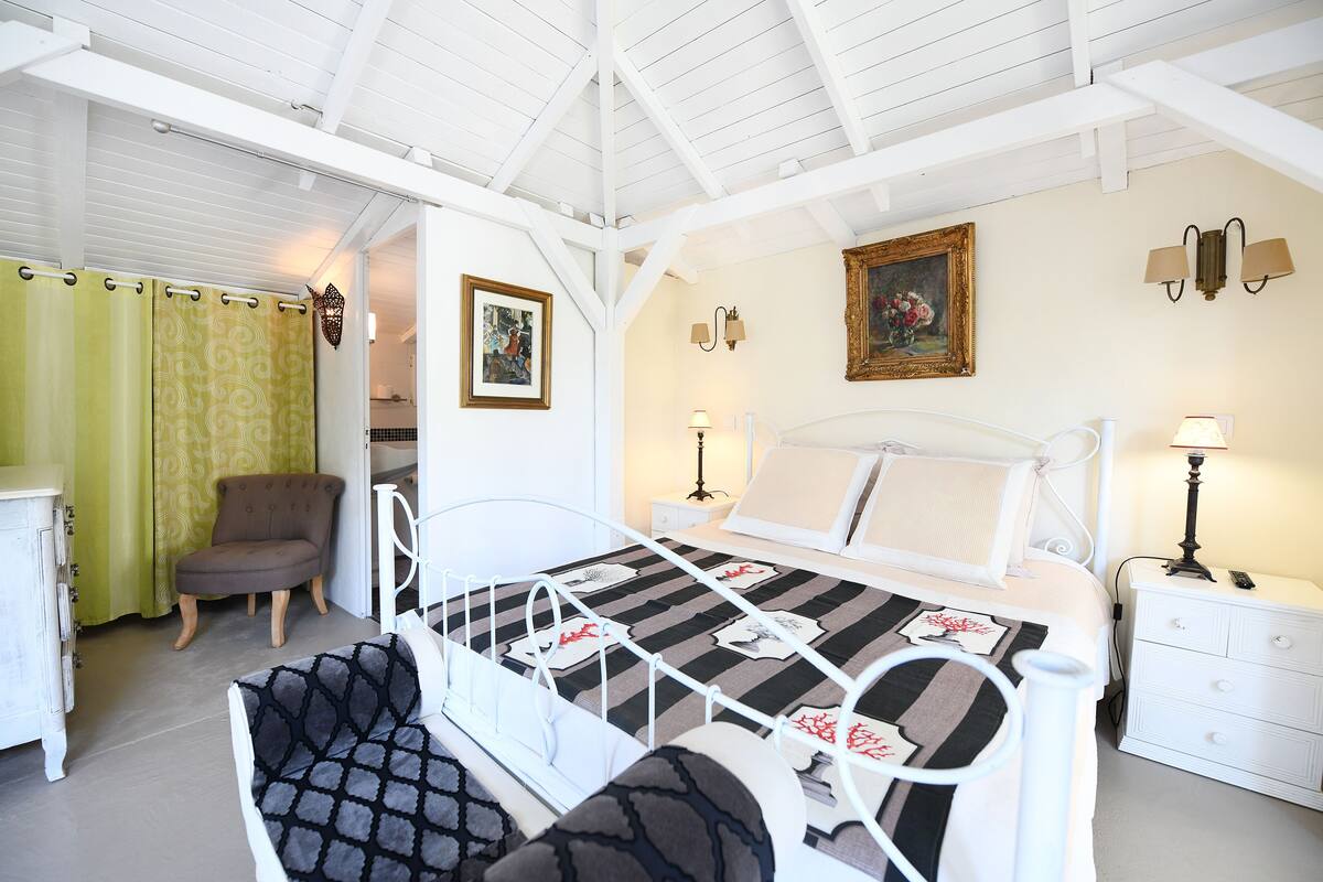 A bedroom with a bed, a chair, a nightstand, and a dresser.