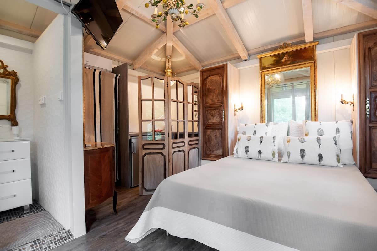 A bedroom with a large bed, wooden wardrobe, and a mirror.
