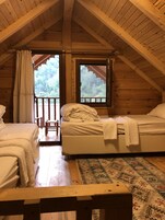 Una cabaña acogedora con dos camas, techo de madera y un ventanal grande con vistas a un bosque.