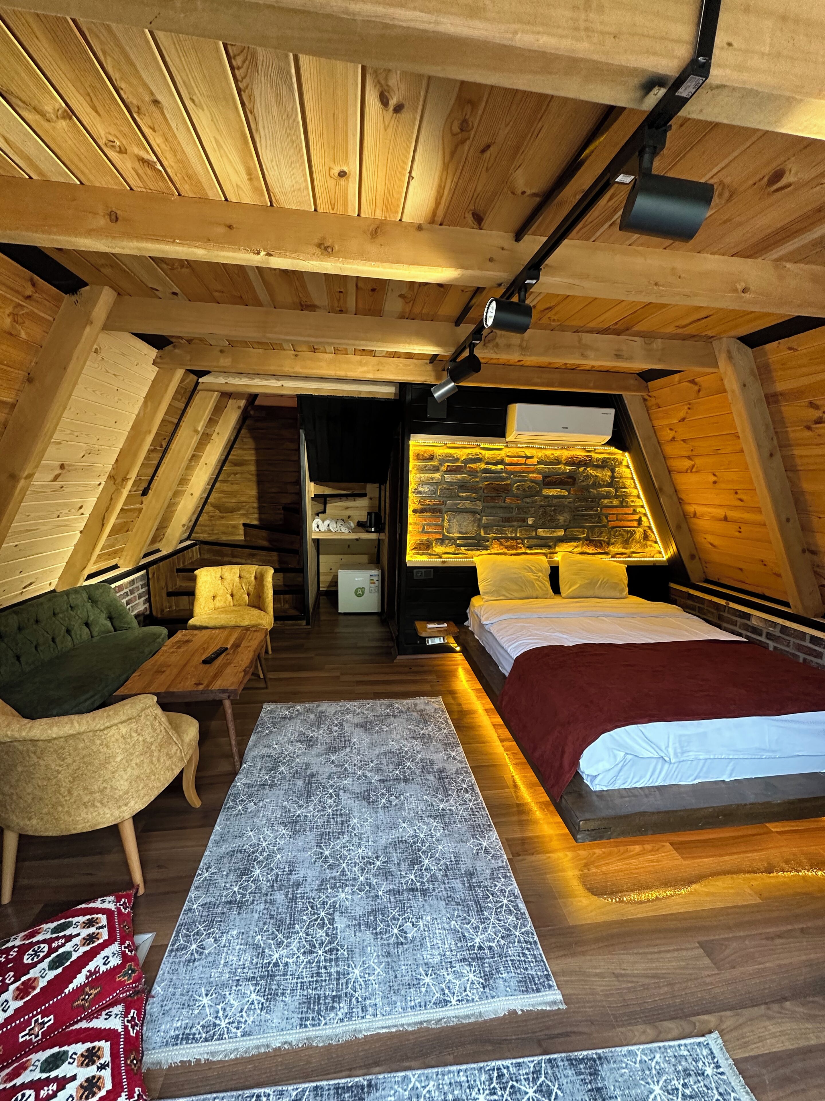 An attic bedroom with a bed, a sofa, a small table, and a built-in fireplace.