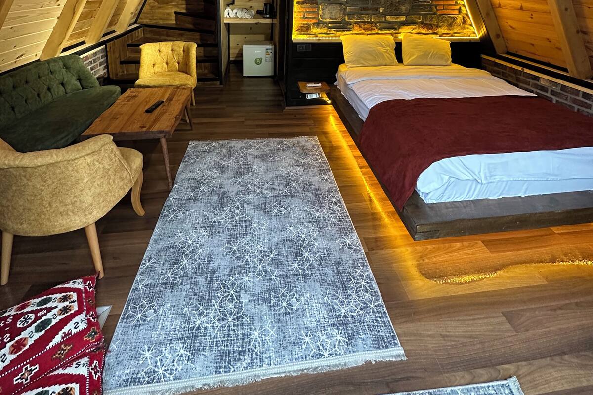 Ein Schlafzimmer im Dachgeschoss mit Bett, Sofa, einem kleinen Tisch und einem eingebauten Kamin.