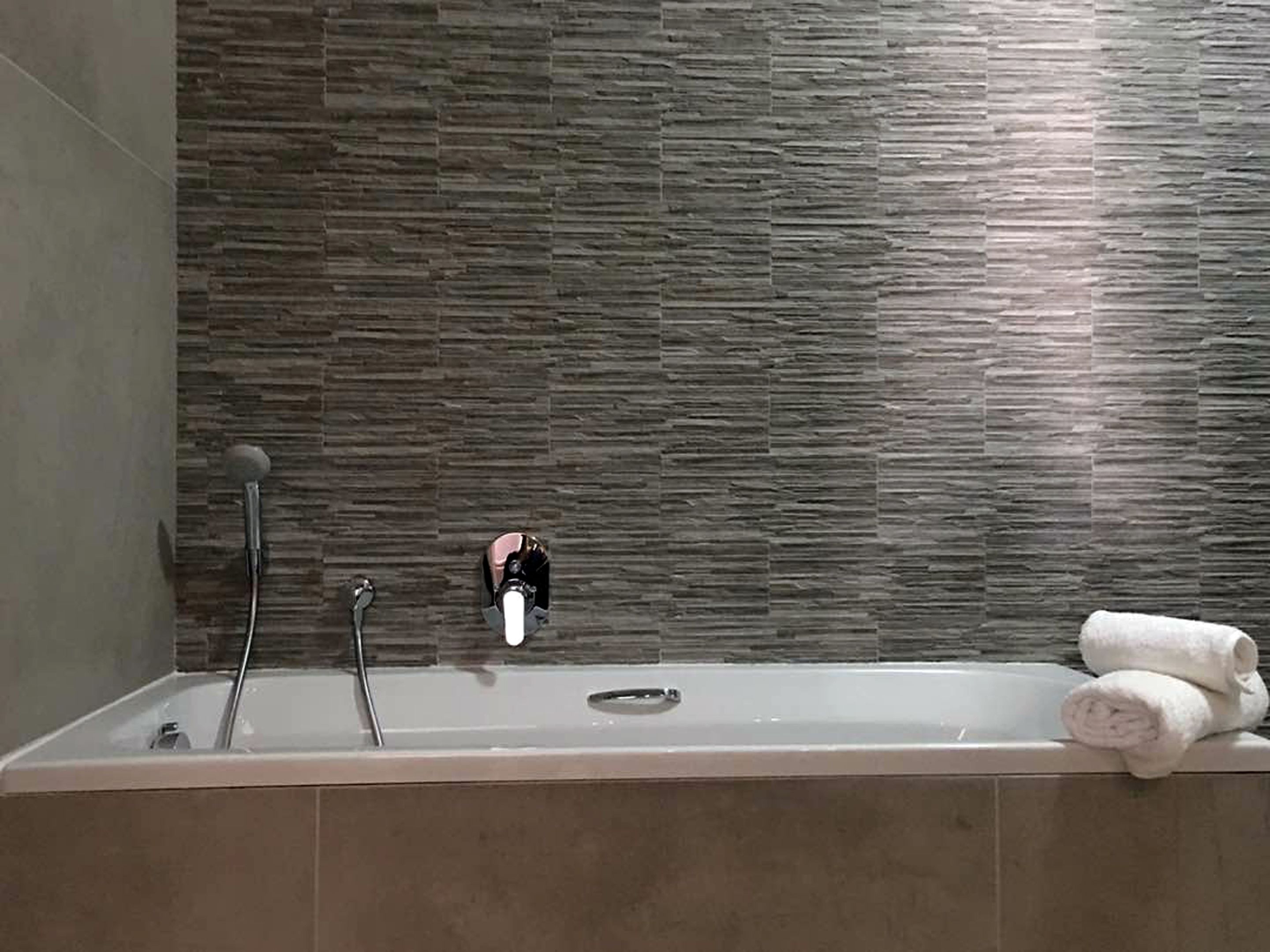Un baño con una bañera, un cabezal de ducha y un perchero para toallas.
