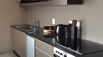 A modern kitchen with a black countertop, stainless steel appliances, and a built-in oven.