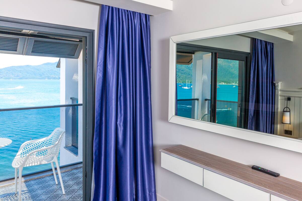 A balcony with a white chair, a large mirror, and a wooden console table.