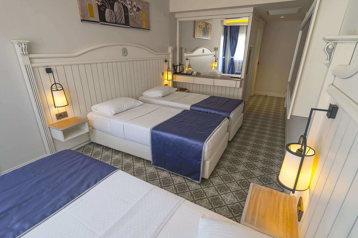 Ein Hotelzimmer mit zwei Betten, einem Nachttisch mit Lampe, einem Spiegel und einem gemusterten Boden.