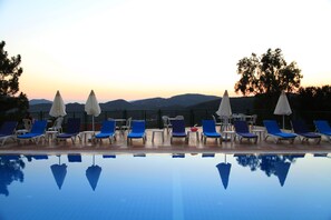 Un espace aménagé au bord de la piscine, avec des chaises longues et des parasols, qui s’harmonise avec le paysage environnant.