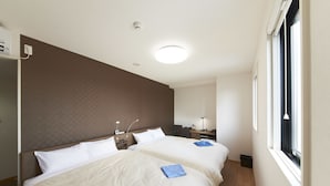 Une chambre d’hôtel avec deux lits, un bureau, une chaise, une lampe et une fenêtre.