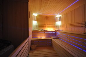A sauna with wooden benches, a bench at the bottom, and a small bucket. - Double Comfort Hotel (Ankara)