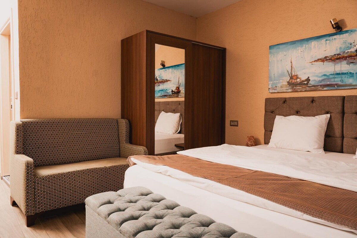 Una habitación de hotel con una cama, un sofá, una silla y un cuadro en la pared.