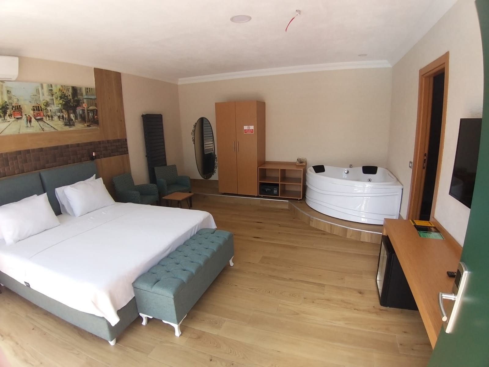 A hotel room with a bed, seating area, a sauna, and a TV.