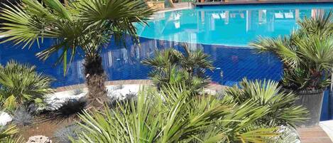 Een buitenzwembad, parasols bij het zwembad en ligstoelen