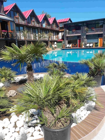 Una piscina al aire libre, sombrillas, sillones reclinables de piscina. Green House Garden Park
