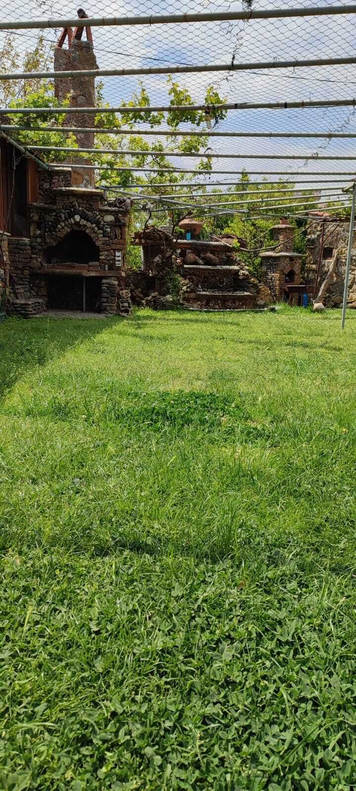 A grassy outdoor area with a stone structure and a metal fence.