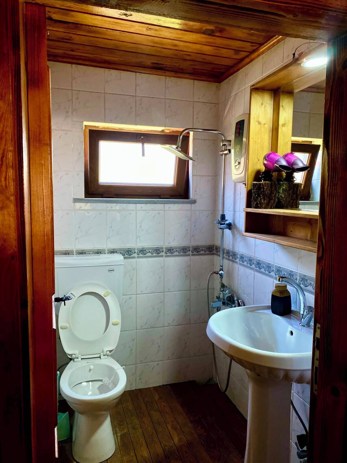 A compact bathroom with a toilet, sink, and shower.
