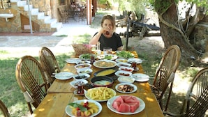 A dining table set outdoors with various dishes, surrounded by wicker chairs.