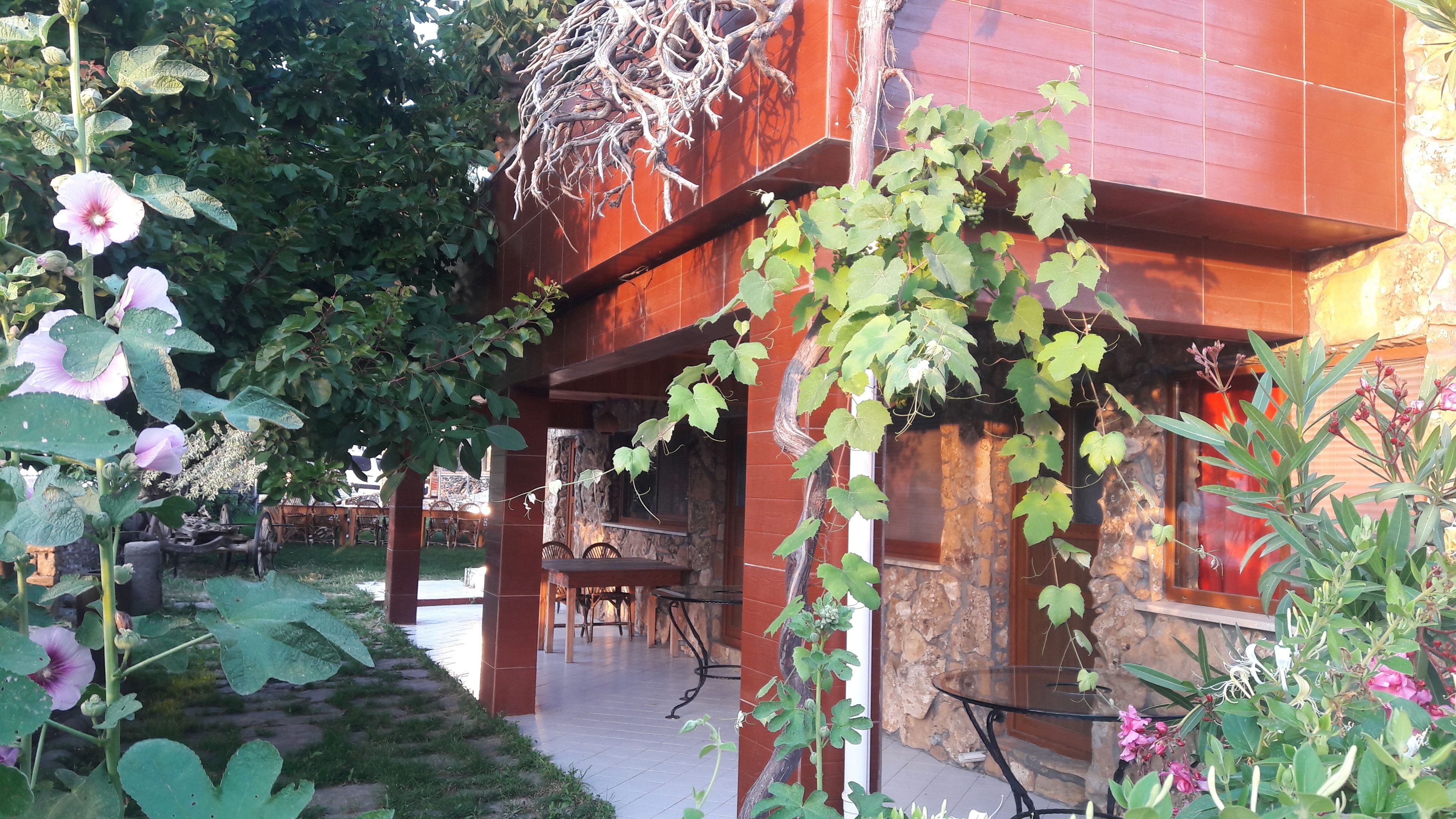Un bâtiment moderne avec une façade en pierre, une table en verre et un espace patio aménagé avec des chaises.