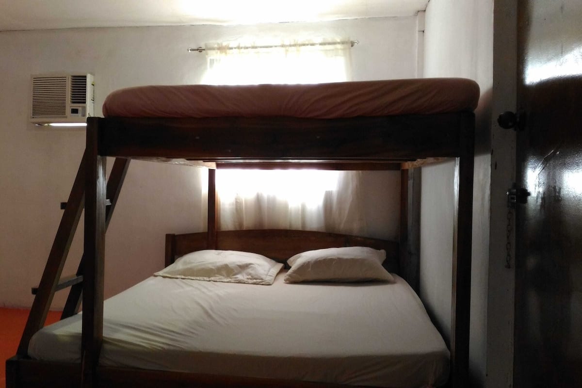 Een stapelbed met een houten frame en witte beddengoed.