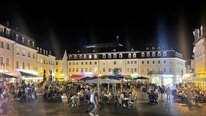 Een drukke marktplaats met terrasjes en gebouwen op de achtergrond.