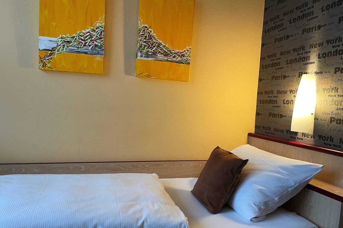 Une chambre d’hôtel avec un lit, des oreillers et deux œuvres d’art murales.