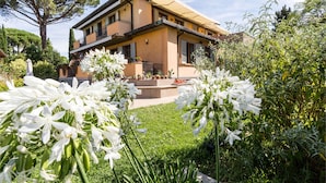 A two-story house with a balcony, surrounded by lush greenery and white flowers. - Relais Villa Jacopone Suites (Florence)