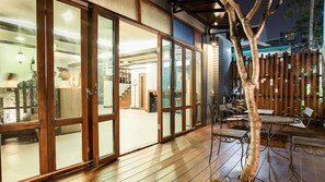 A wooden deck with a dining area, glass sliding doors, and a tree. - B2 Nimman Premier Hotel (Chiang Mai)