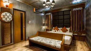 A modern bedroom with a wooden bed, bedside tables, a bench, a headboard, and a chandelier. - B2 Nimman Premier Hotel (Chiang Mai)