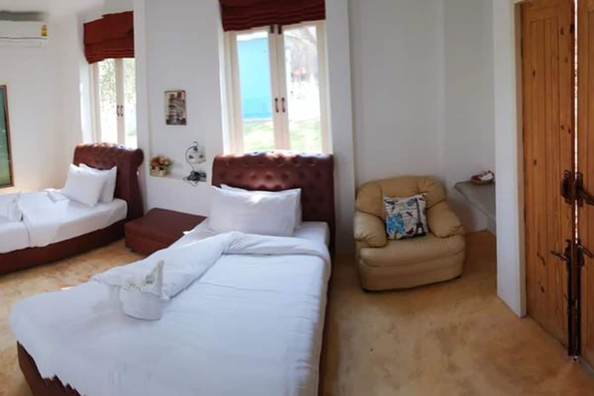 A bedroom with two beds, a TV, a wooden door, and a window.