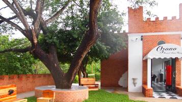 A courtyard with a large tree, outdoor seating, and a brick building with a sign reading "Ozone".