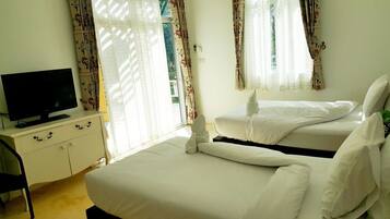 A hotel room with two beds, a TV on a dresser, and floral curtains.
