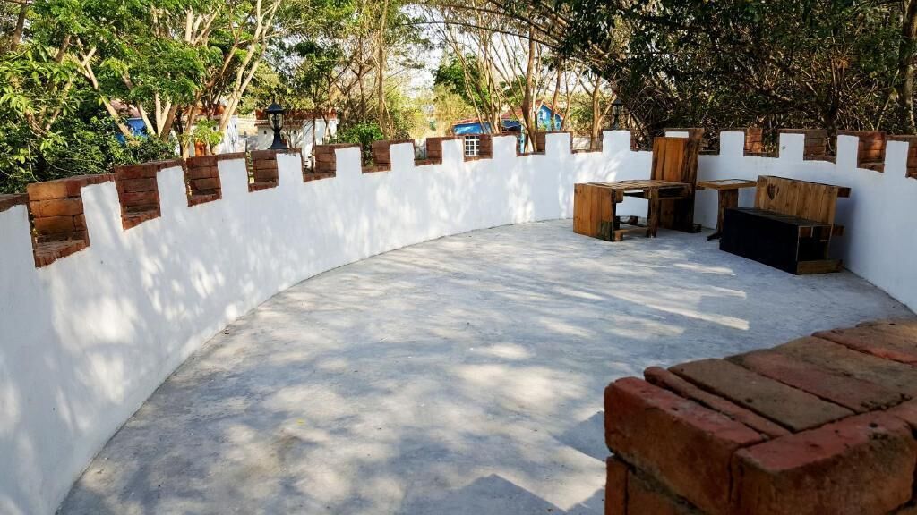 A curved outdoor seating area with a white wall and brick accents, surrounded by trees.