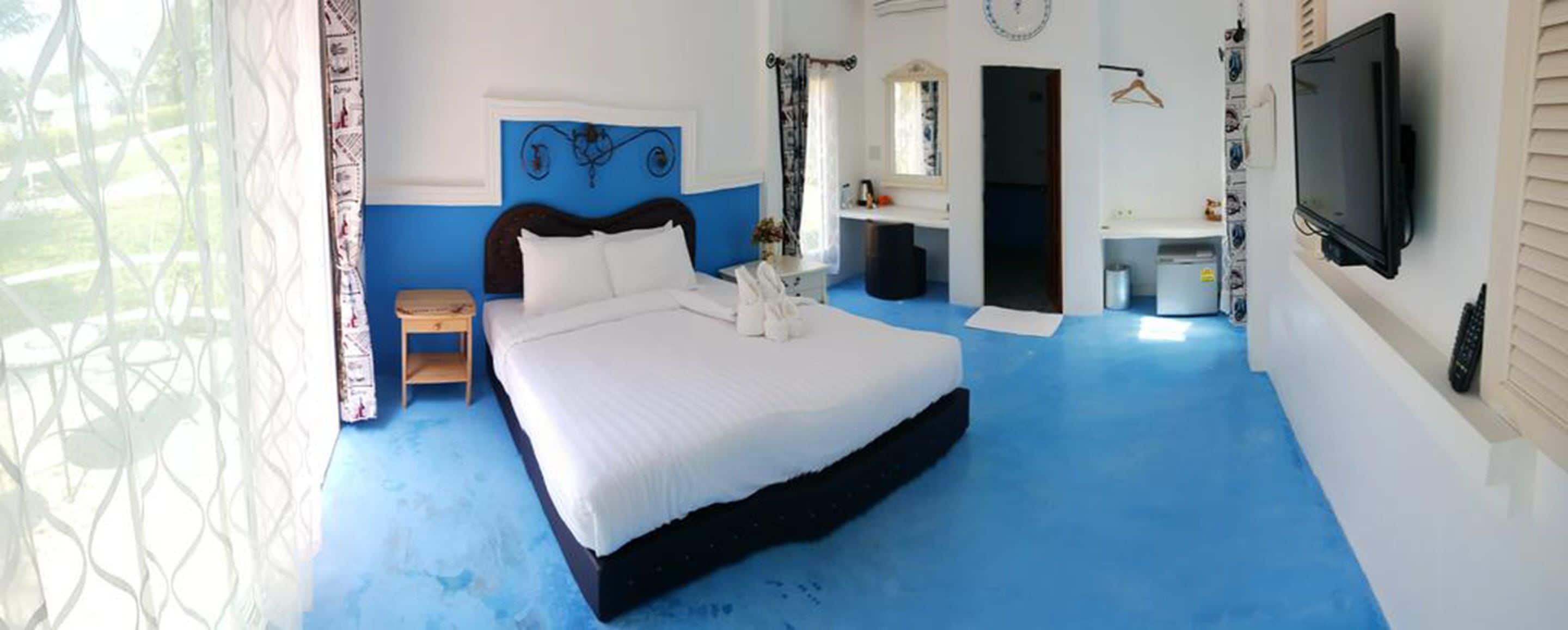 A bedroom with a large bed, a TV, a desk, and a bathroom.