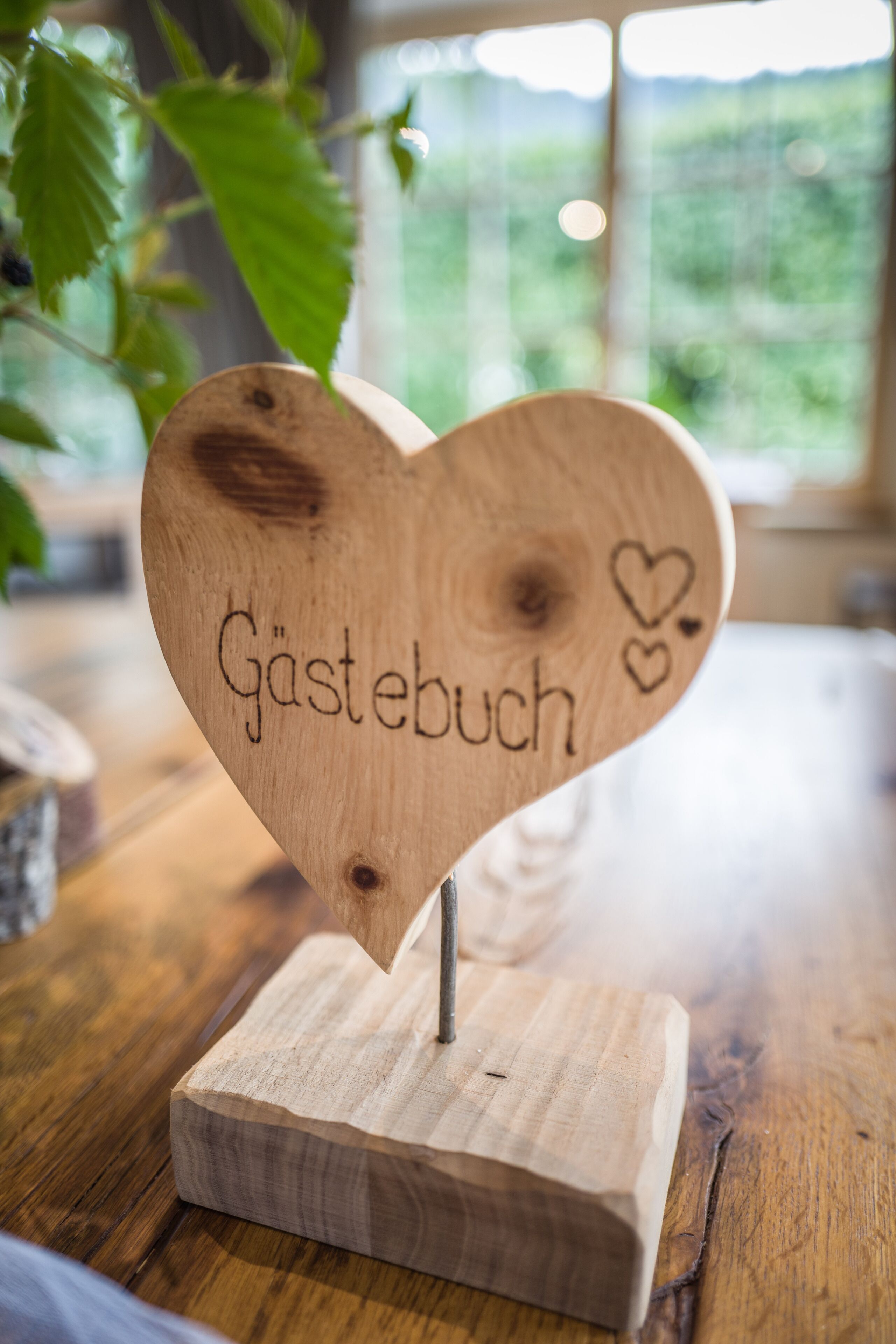 Un letrero con forma de corazón de madera con el texto 'Gästebuch'.