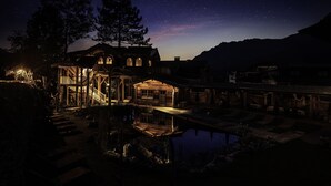 A rustic cabin with a wooden deck, a small dock, and a clear night sky.