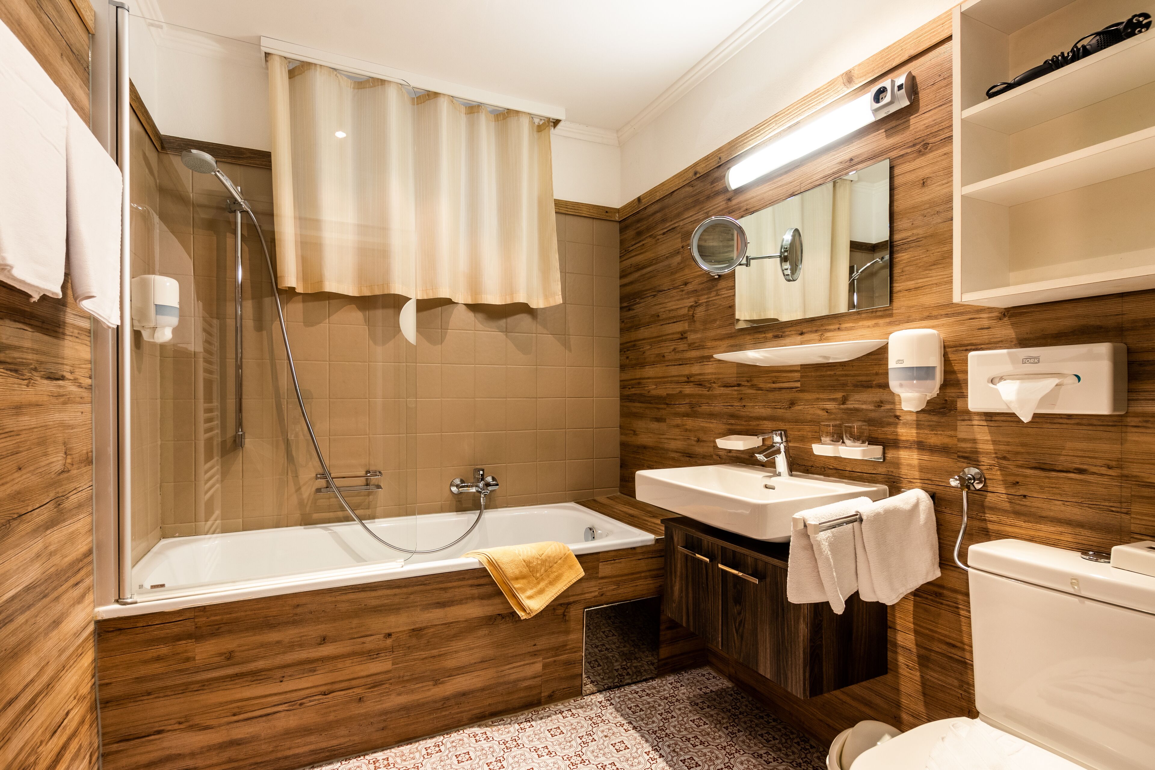 A modern bathroom with a bathtub, shower, and toilet.