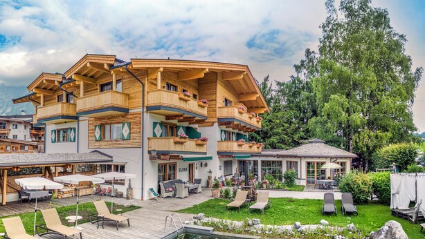 A multi-story wooden building with balconies, a pool, and outdoor seating areas.