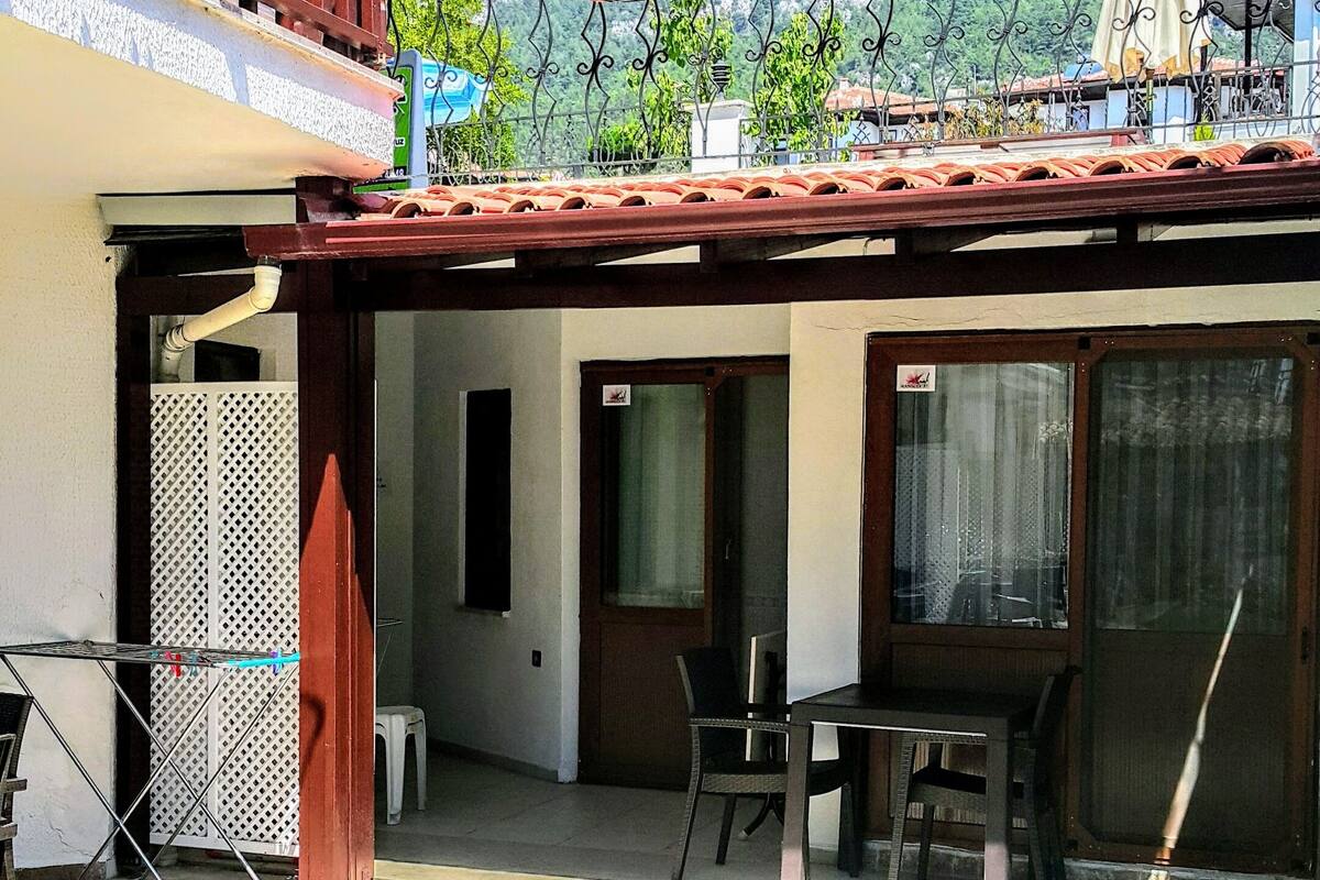 A courtyard with a tiled floor, a table and chairs, and a view of a mountainous landscape.