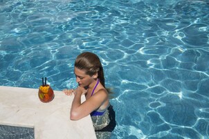 Una piscina al aire libre, sombrillas, sillones reclinables de piscina