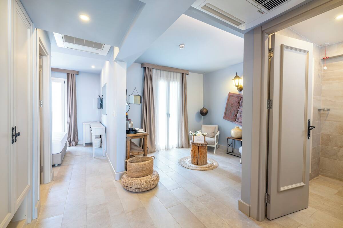 A hotel room with a bed, bedside table, lamp, and a view of the hallway.