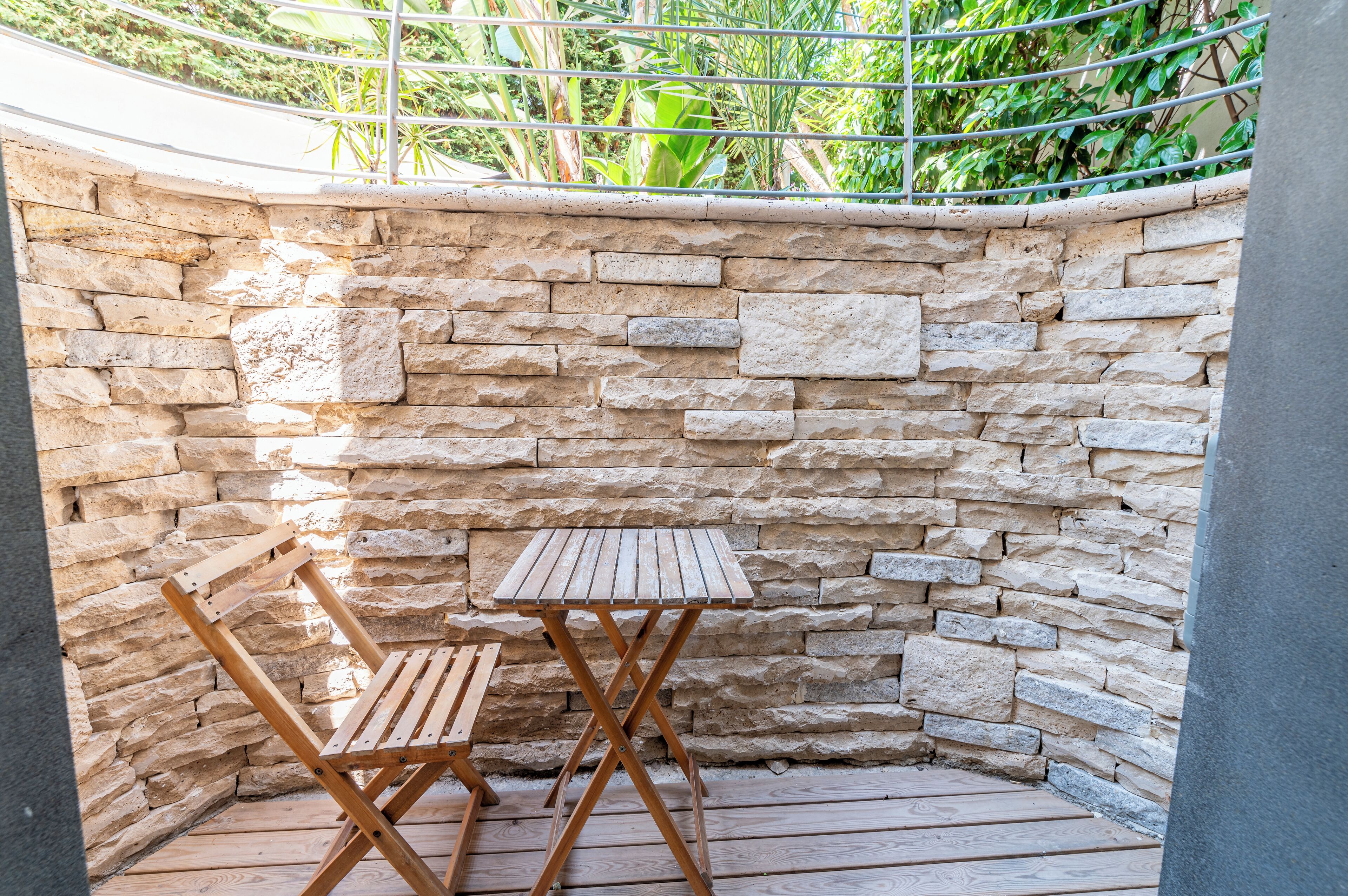 Un muro de piedra con una mesa y sillas de madera en un rincón.