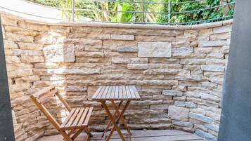 Un muro de piedra con una mesa y sillas de madera en un rincón.