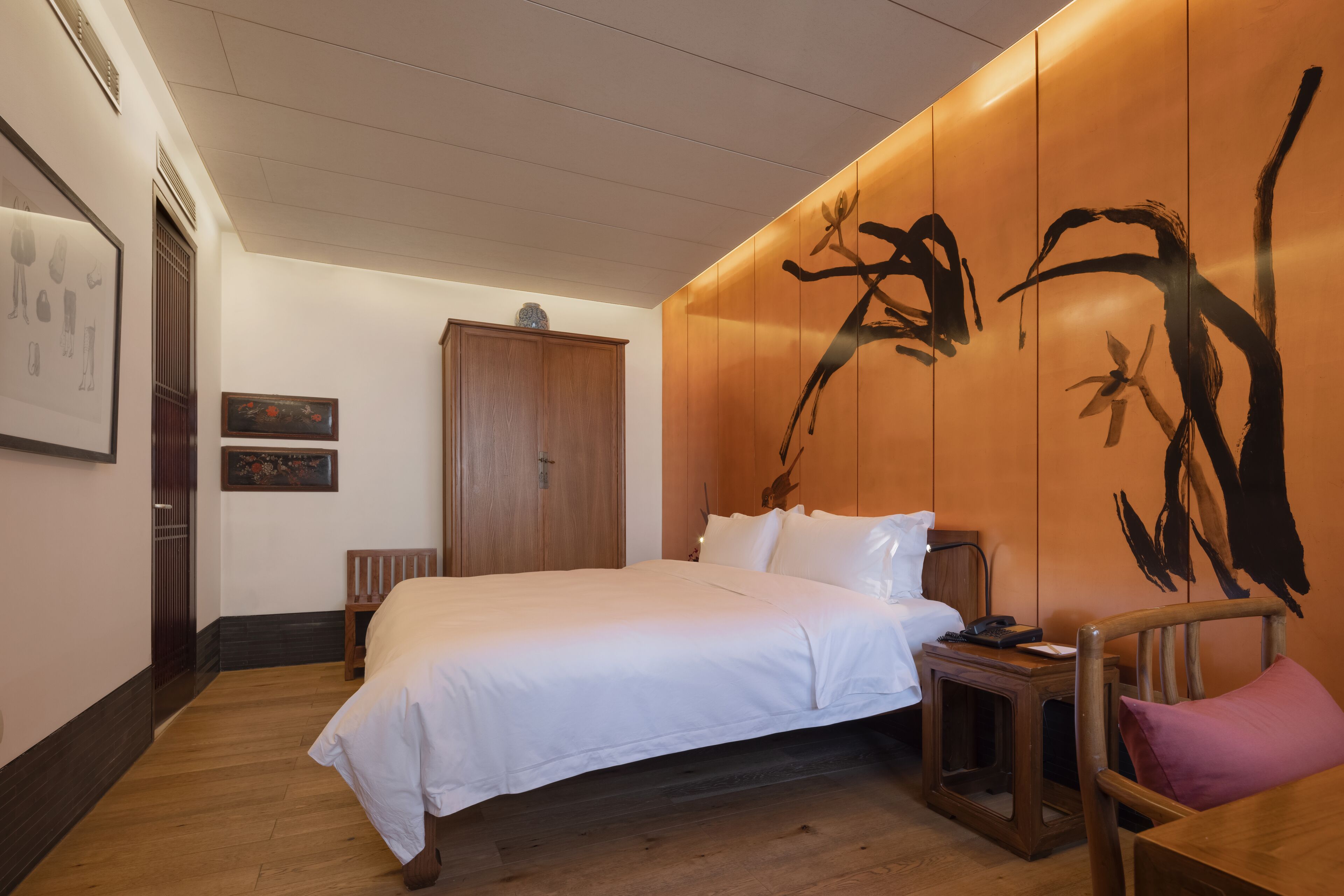 Een hotelkamer met een groot bed, een houten hoofdbord en een muur met een abstract schilderij.