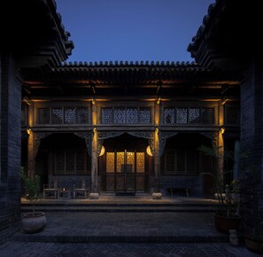 A traditional building with a tiled roof, wooden doors, and a brick facade.